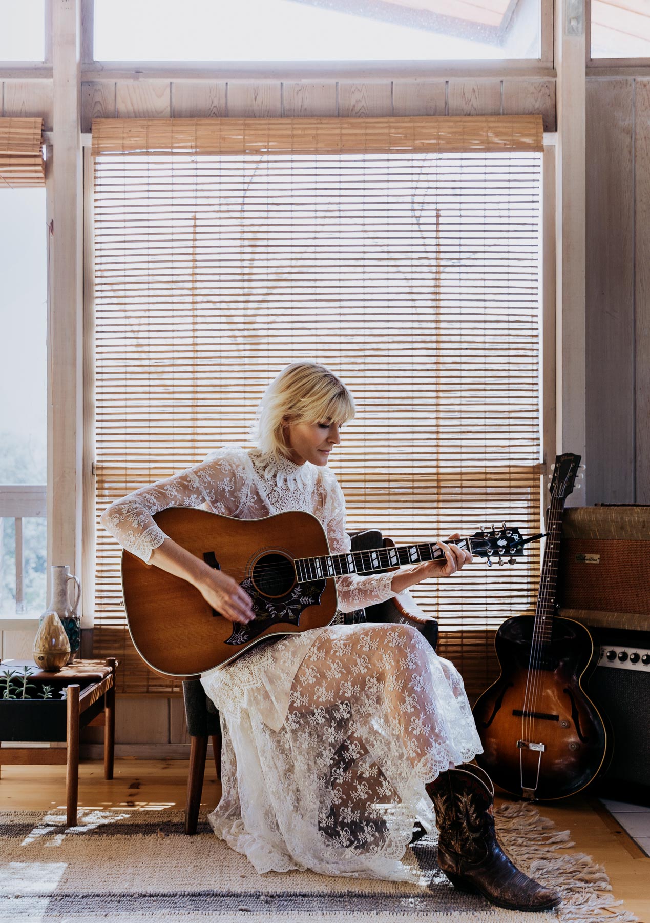 Musician Marnie Herald playing her guitar in her living room.