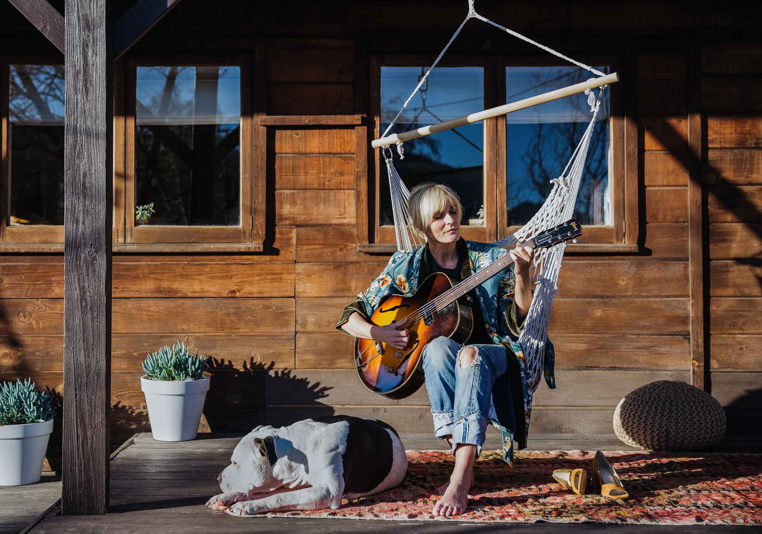 Musician Marnie Herald playing her guitar on her front porch
